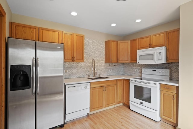 kitchen with white appliances, backsplash, a sink, and light countertops