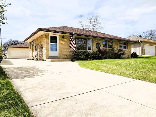single story home featuring brick siding, an outbuilding, a front yard, and a detached garage