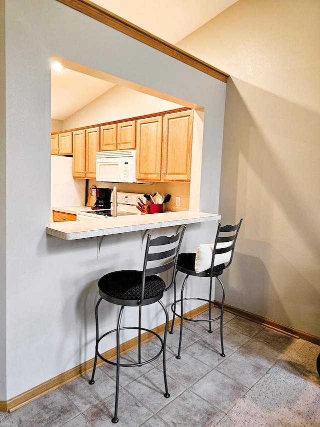 850 Evergreen Dr Unit 8, Hartford, WI 53027 - kitchen with baseboards, white microwave, and a kitchen bar