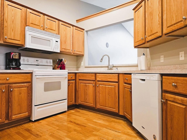 850 Evergreen Dr Unit 8, Hartford, WI 53027 - kitchen featuring a sink, brown cabinets, light wood-type flooring, and white appliances