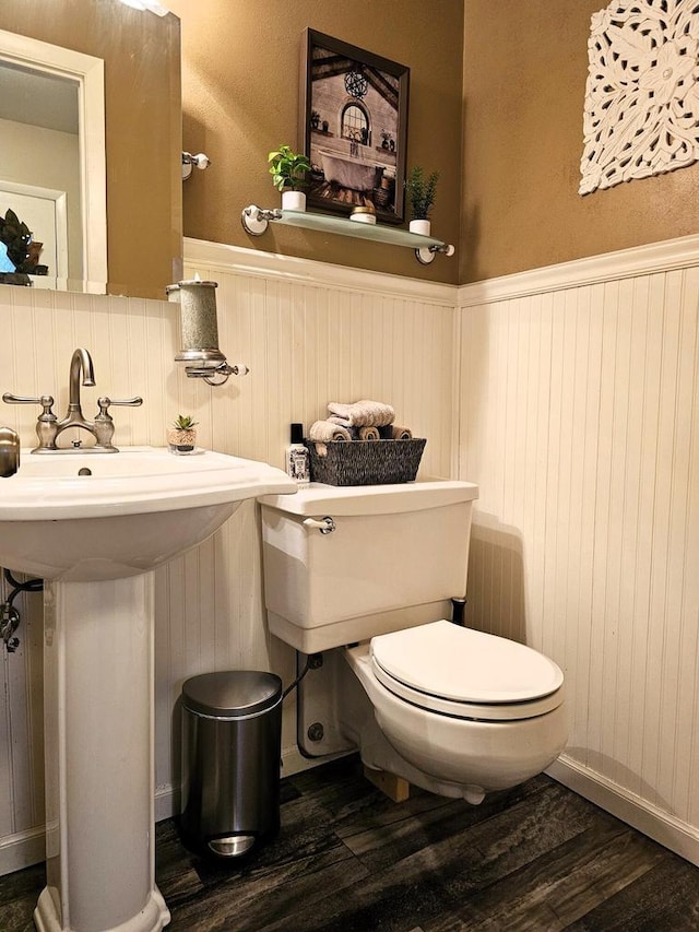 bathroom featuring wainscoting, toilet, and wood finished floors