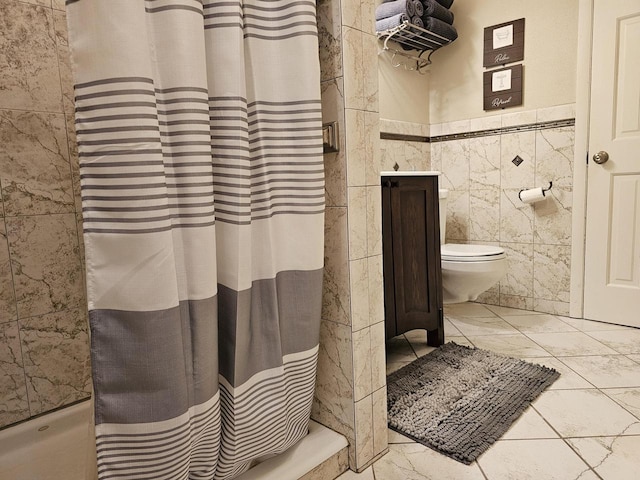 full bathroom with toilet, tile walls, marble finish floor, and a wainscoted wall