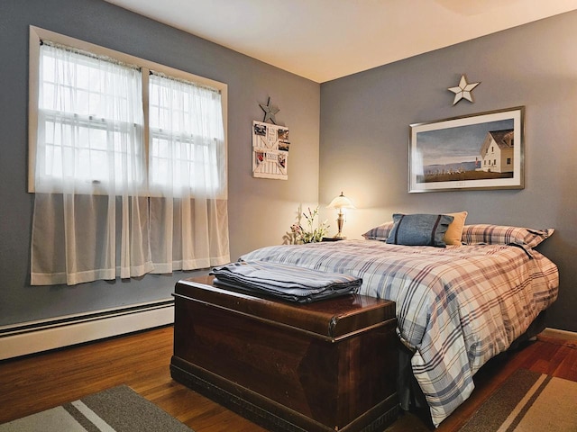 bedroom with wood finished floors and a baseboard radiator
