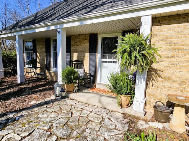 property entrance featuring a porch and brick siding