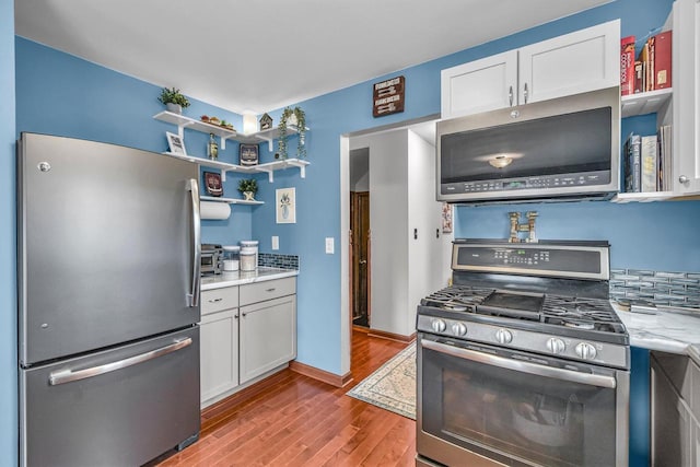 kitchen featuring open shelves, appliances with stainless steel finishes, wood finished floors, and white cabinets