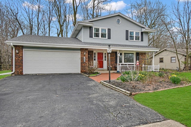view of front facade featuring covered porch, driveway, a front yard, a garage, and brick siding