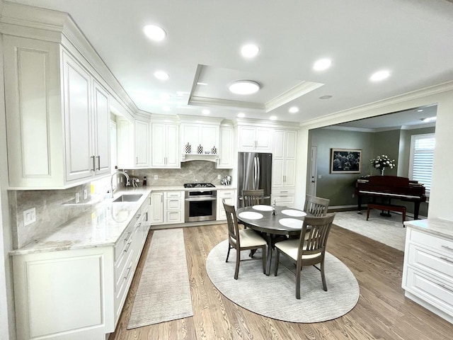 kitchen featuring crown molding, a sink, light wood finished floors, and stainless steel appliances