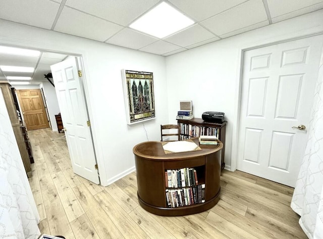 dining space with light wood-style floors, baseboards, and a paneled ceiling