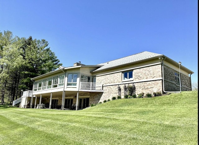 back of property featuring stairs, brick siding, a sunroom, a chimney, and a yard