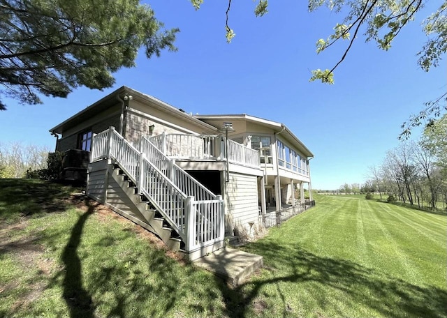 rear view of property featuring a yard, stairway, and a deck