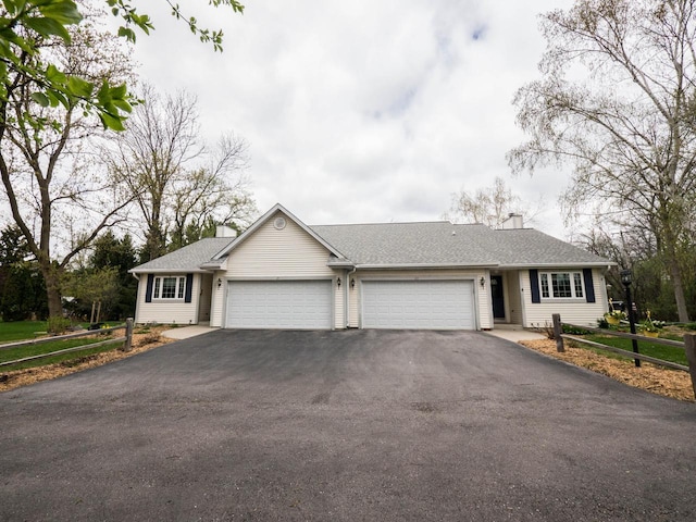 view of front of property featuring a garage, a chimney, driveway, and roof with shingles