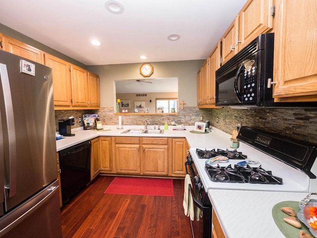 kitchen featuring backsplash, dark wood-style flooring, a sink, light countertops, and black appliances