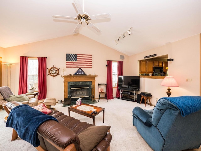 living area featuring a ceiling fan, vaulted ceiling, a premium fireplace, and light colored carpet