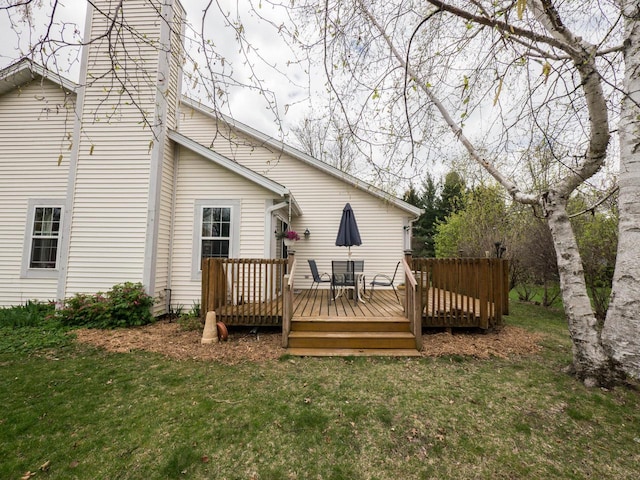rear view of property with a chimney, a yard, and a deck