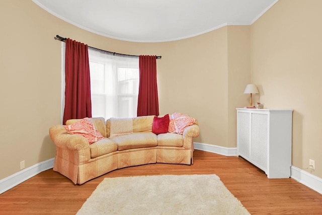 living area with crown molding, baseboards, and wood finished floors