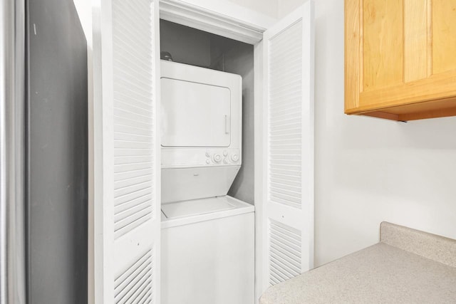 clothes washing area with stacked washing maching and dryer and laundry area