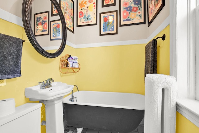 bathroom with a freestanding bath, tile patterned floors, and toilet
