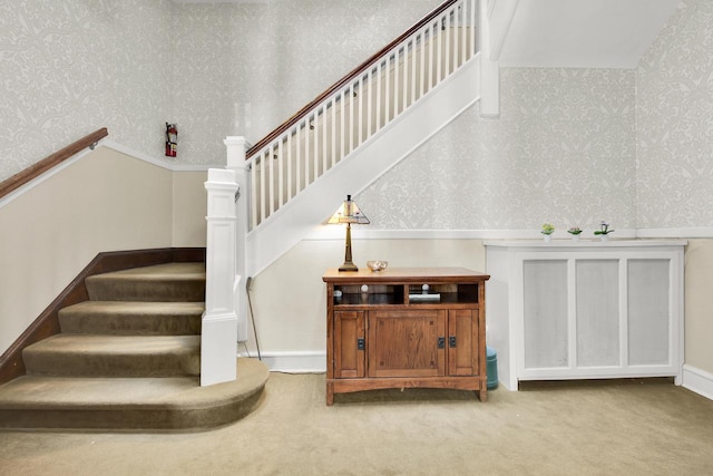 stairway with carpet floors and wallpapered walls