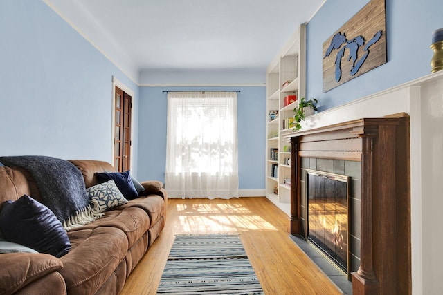 living area with baseboards, a fireplace, and light wood-style flooring