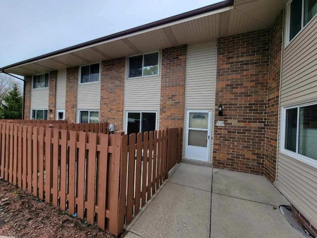rear view of property with brick siding, fence, and a patio