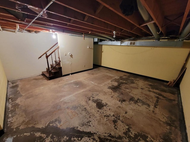 unfinished below grade area featuring visible vents and stairway