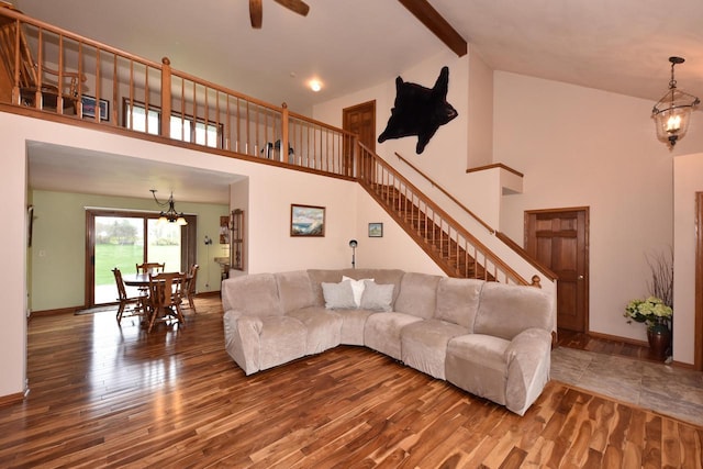 living room with stairs, wood finished floors, baseboards, high vaulted ceiling, and ceiling fan with notable chandelier