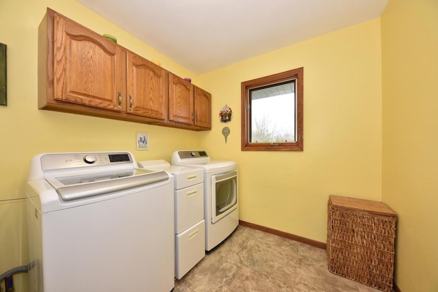 washroom with washing machine and clothes dryer, baseboards, and cabinet space