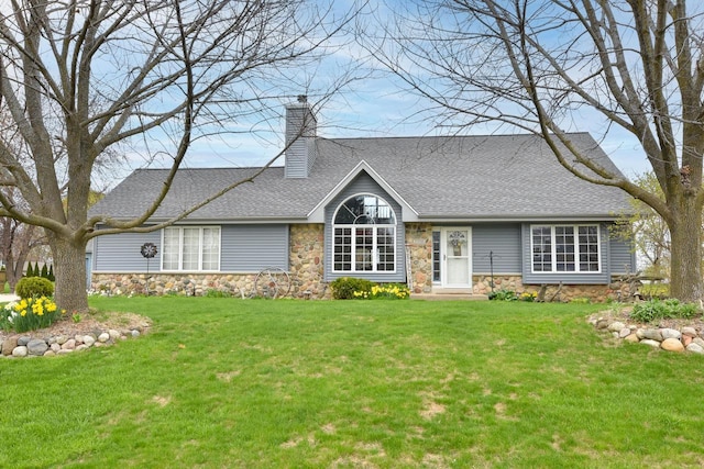 view of front facade with a chimney, roof with shingles, a front yard, and stone siding