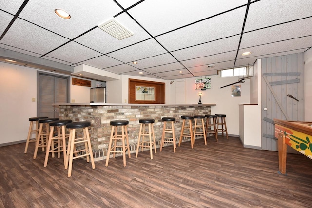 bar featuring freestanding refrigerator, baseboards, bar, and wood finished floors