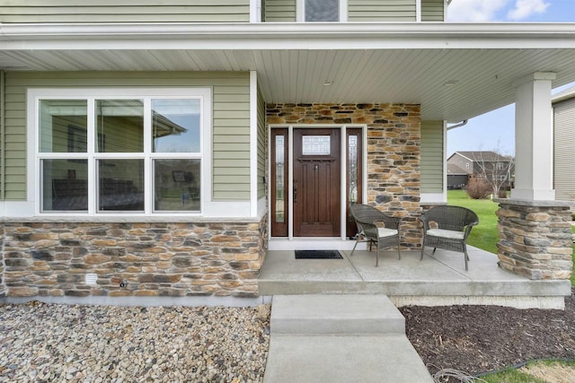 view of exterior entry with a porch and stone siding