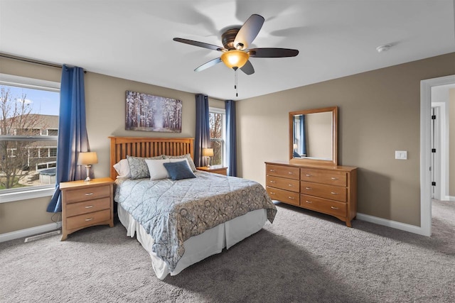 carpeted bedroom featuring baseboards, ceiling fan, and multiple windows