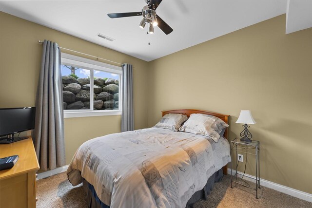carpeted bedroom with baseboards, visible vents, and ceiling fan