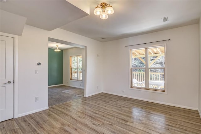 603 Dodge St, Eau Claire, WI 54701 - spare room with visible vents, baseboards, wood finished floors, and a notable chandelier