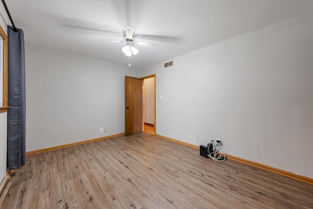 spare room featuring baseboards, a ceiling fan, wood finished floors, and visible vents