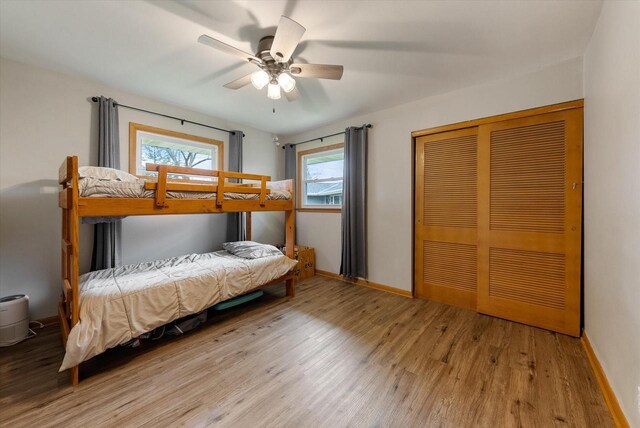 bedroom featuring a closet, a ceiling fan, baseboards, and wood finished floors