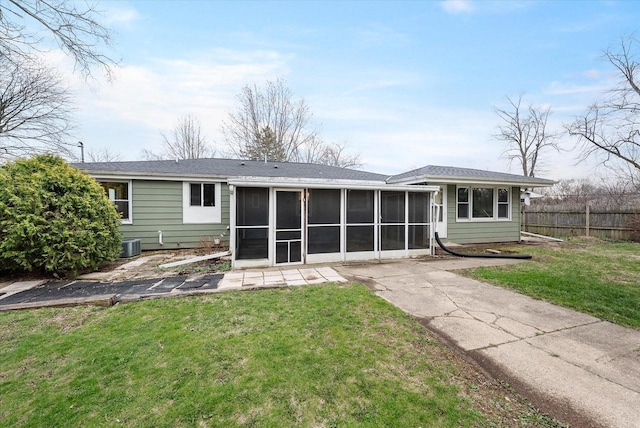 rear view of house with a lawn, fence, and a sunroom
