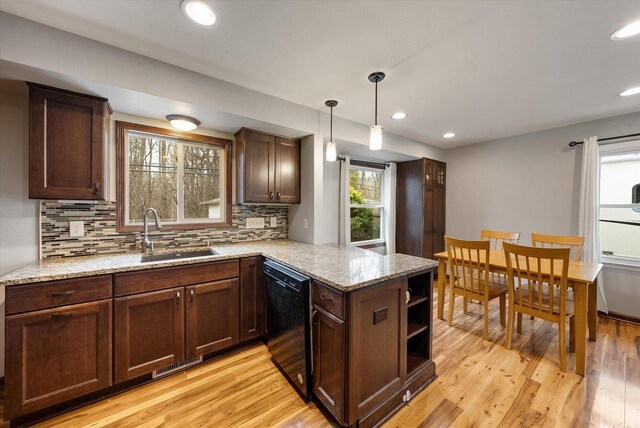 kitchen featuring a sink, light wood-style floors, dishwasher, a peninsula, and tasteful backsplash