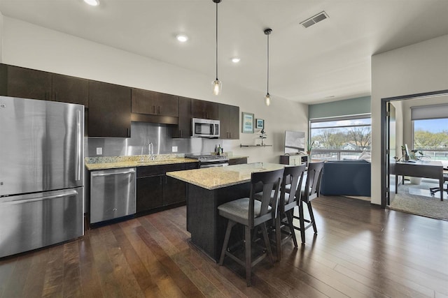 kitchen featuring a kitchen bar, dark wood-style flooring, visible vents, appliances with stainless steel finishes, and a center island