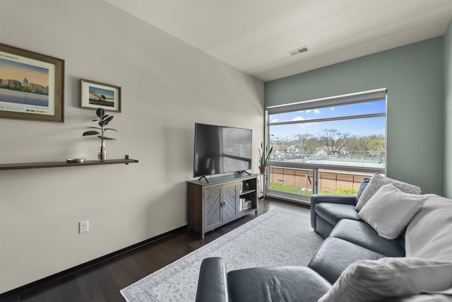 living area with visible vents, baseboards, and wood finished floors