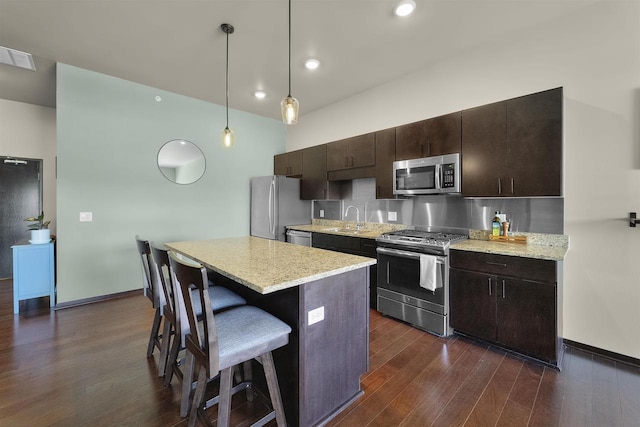 kitchen with a kitchen island, a kitchen breakfast bar, a sink, dark wood finished floors, and stainless steel appliances