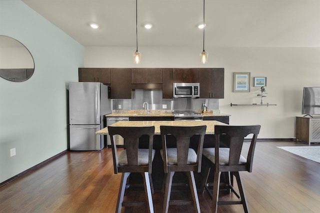 kitchen featuring a kitchen island, dark brown cabinets, a breakfast bar area, a sink, and stainless steel appliances