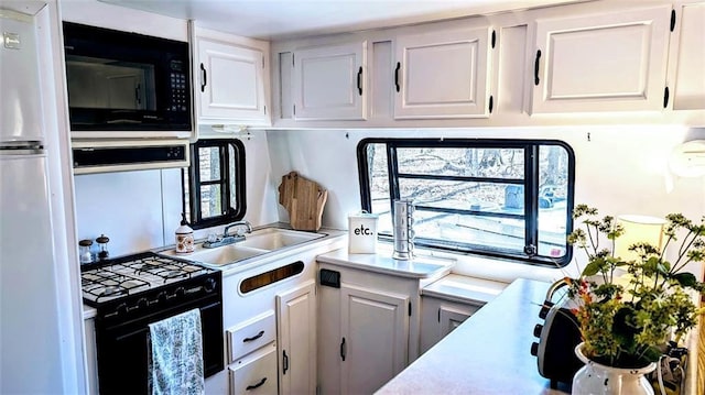 kitchen with light countertops, white cabinets, and black appliances