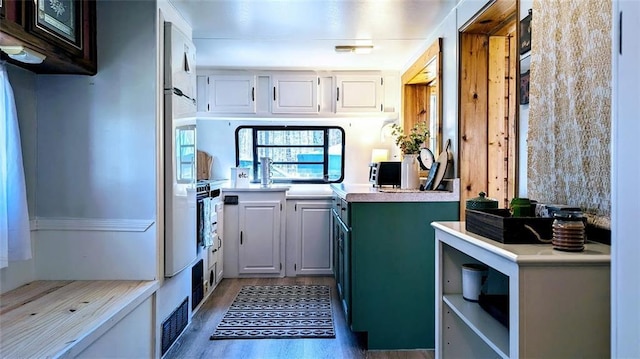 kitchen with light countertops, white cabinetry, and wood finished floors