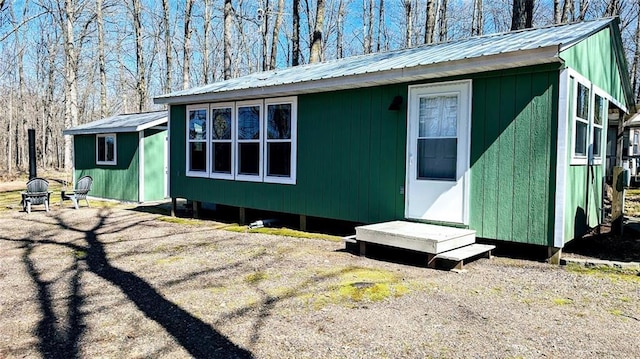 view of property exterior with an outdoor structure, entry steps, and metal roof
