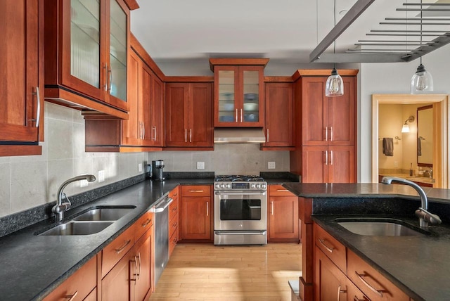 kitchen featuring a sink, appliances with stainless steel finishes, light wood finished floors, and decorative light fixtures