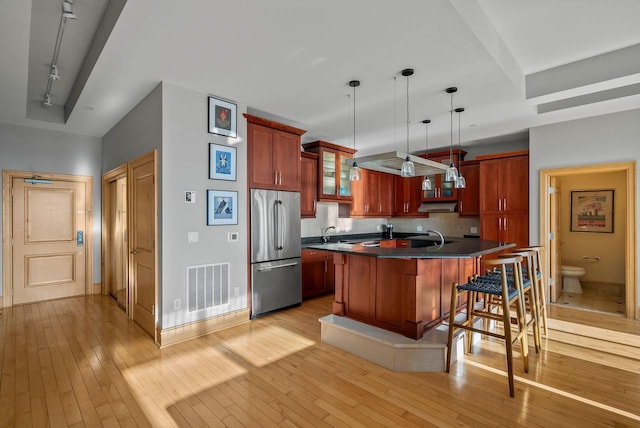 kitchen featuring a kitchen bar, visible vents, dark countertops, light wood finished floors, and high end fridge