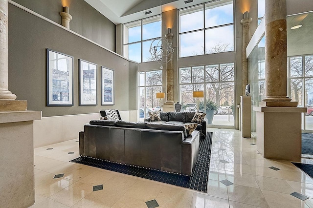 tiled living area with a high ceiling and decorative columns
