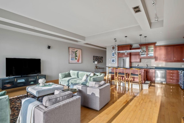 living area with rail lighting, visible vents, baseboards, and light wood-type flooring