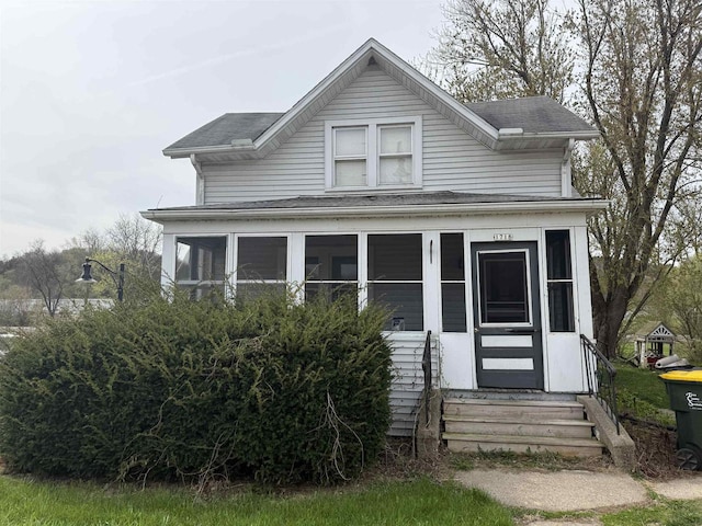 bungalow-style house featuring roof with shingles, entry steps, and a sunroom