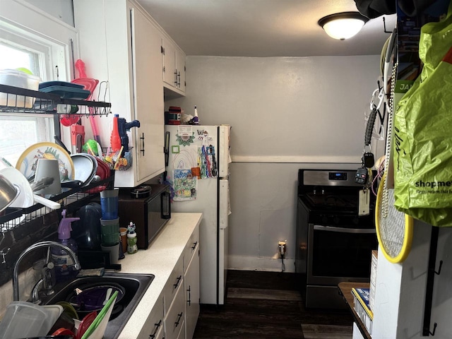 kitchen featuring white cabinets, electric range, a sink, light countertops, and dark wood-type flooring